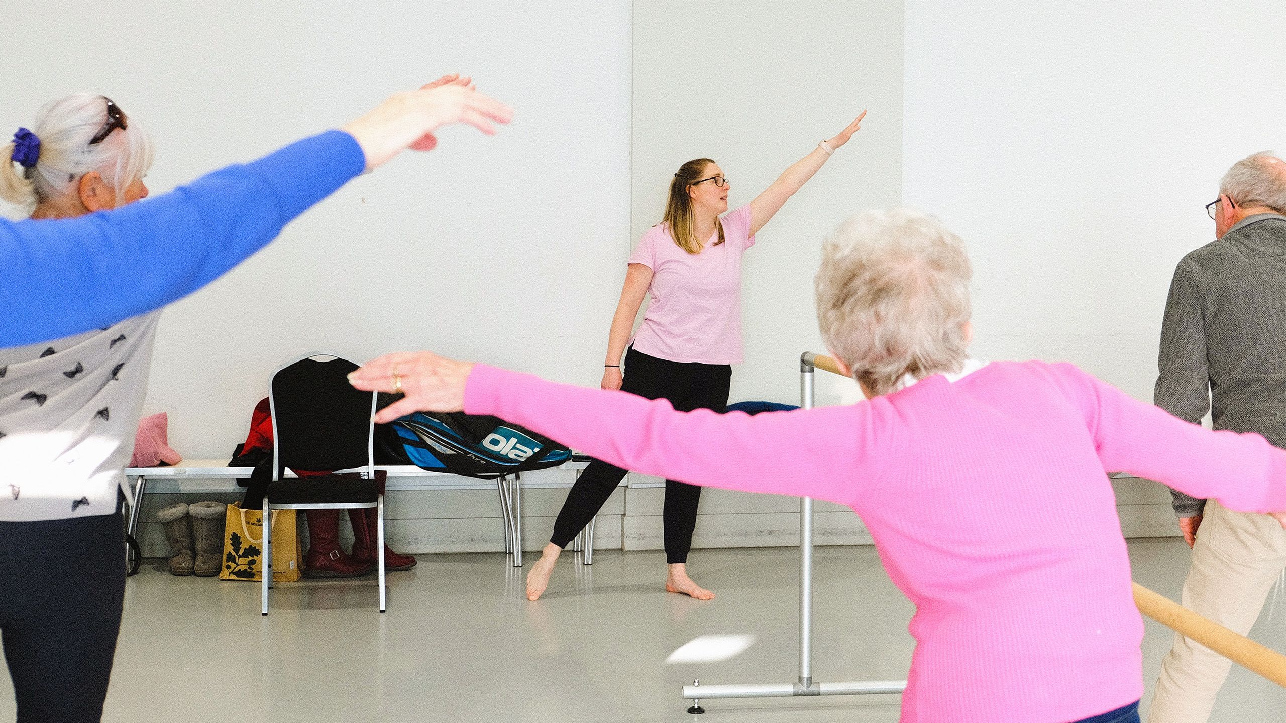 Teacher and attendees using ballet bar to stretch in dance class