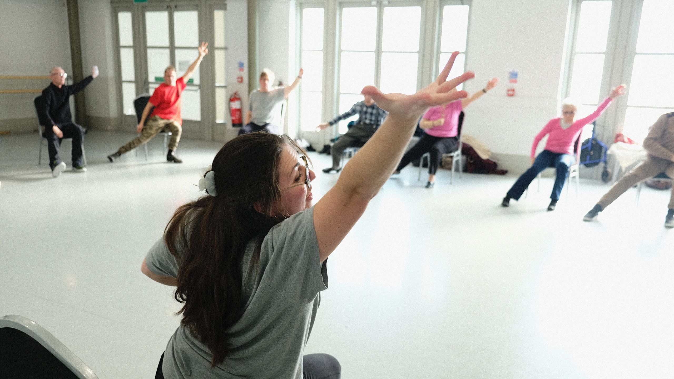Image of teacher and attendees stretching arms at Parkinson's Dance class