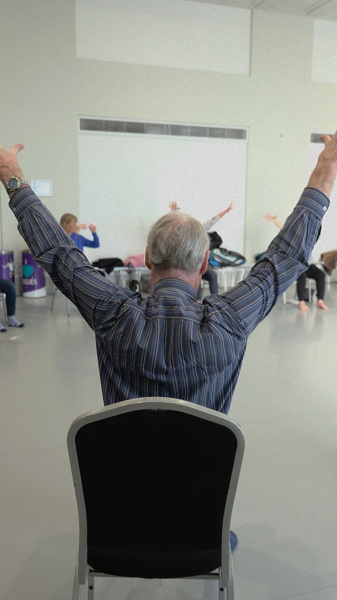 The back of Parkinson's dance class attendee raising both hands
